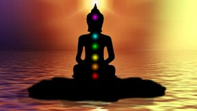 Buddhistsatva in a perfect sillouhette with glowing chakras sitting in the middle of a still lake. Bruce Clifton